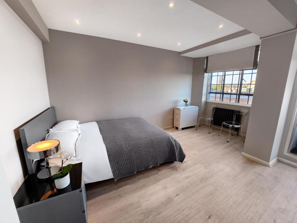 a bedroom with a large bed and a fireplace at Chelsea Flat 10 mins Harrods, Balcony, Gym, Air Conditioning in London