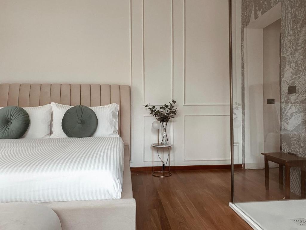 a white bedroom with a bed and a vase of flowers at Villa Maldestra in Rimini