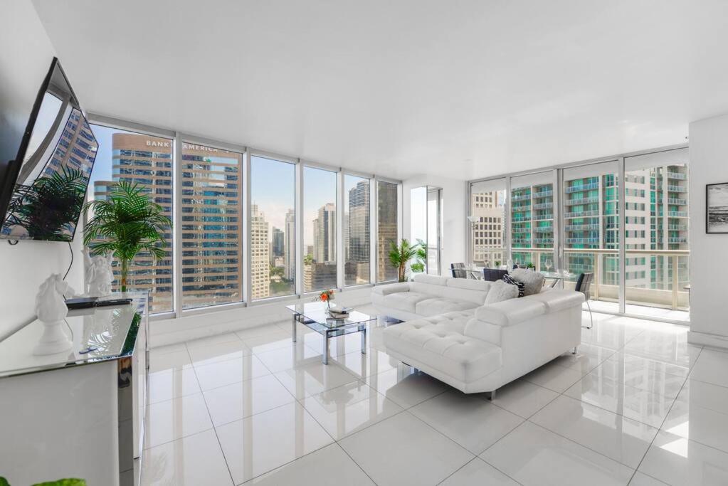 una sala de estar con muebles blancos y ventanas grandes. en Luxury Condo with Panoramic Views at Icon Brickell, en Miami