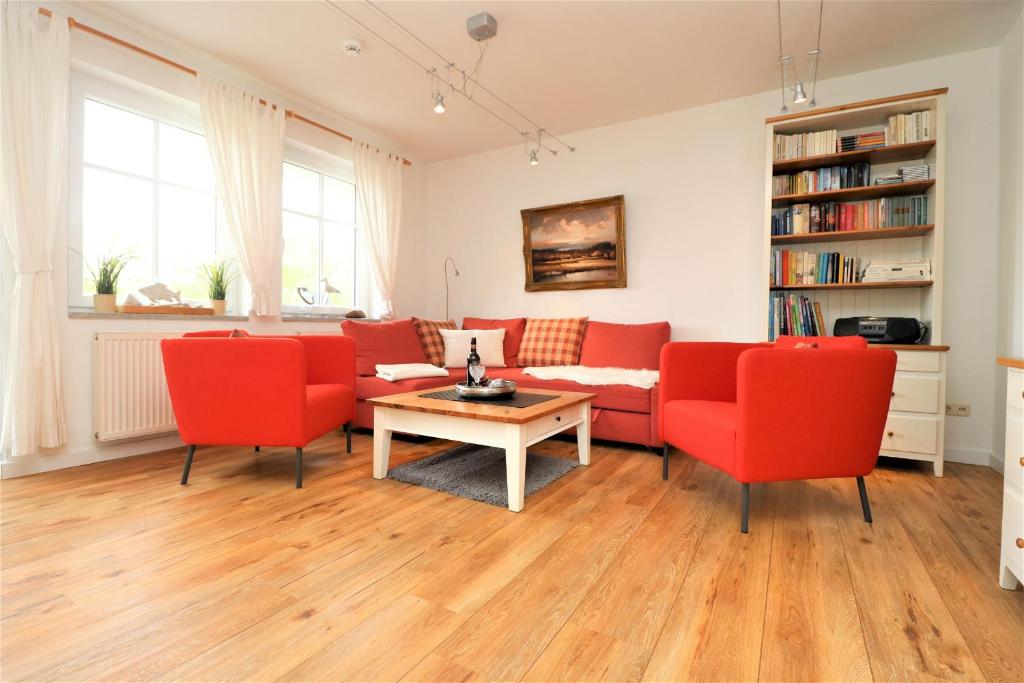 a living room with red chairs and a table at Wohnpark Strandstraße App 12 in Wustrow