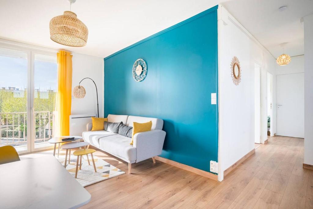 een woonkamer met een bank en een blauwe muur bij Appartement 3 Chambres - Climatisation - Parking in Portet-sur-Garonne