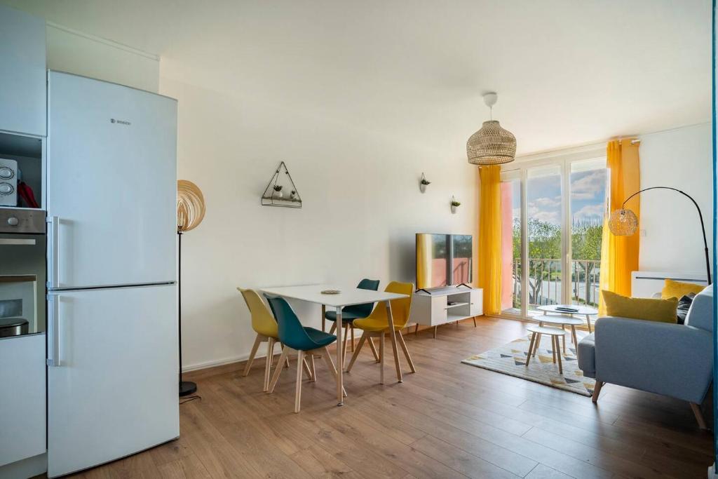 kuchnia i salon ze stołem i krzesłami w obiekcie Appartement 3 Chambres - Climatisation - Parking w mieście Portet-sur-Garonne