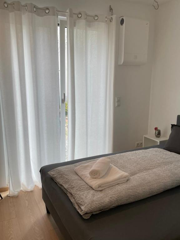 Black Forest Apartments في غينغنباخ: غرفة نوم بسرير والستائر بيضاء