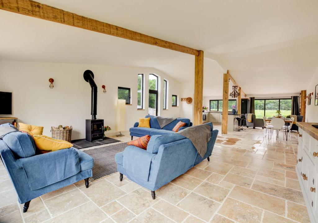 a living room with two blue couches and a fireplace at Roe Deer Barn in Briston