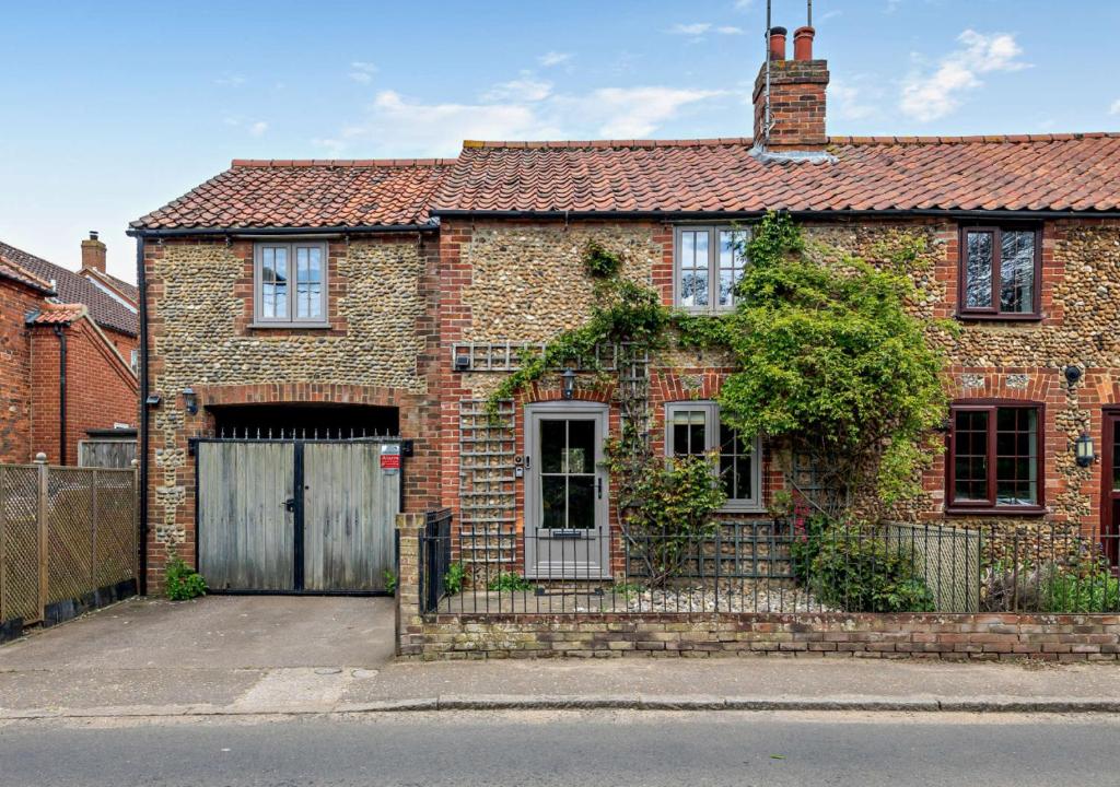 a brick house with a gate and a garage at Rose Cottage - Sedgeford in Sedgeford