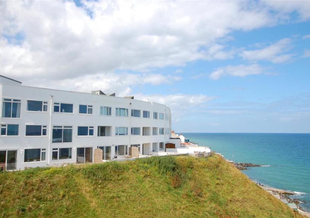 a white building on a hill next to the ocean at Seaspray in Sheringham