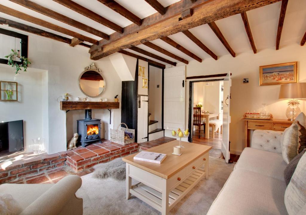 a living room with a fireplace and a couch at Robin Cottage in North Elmham