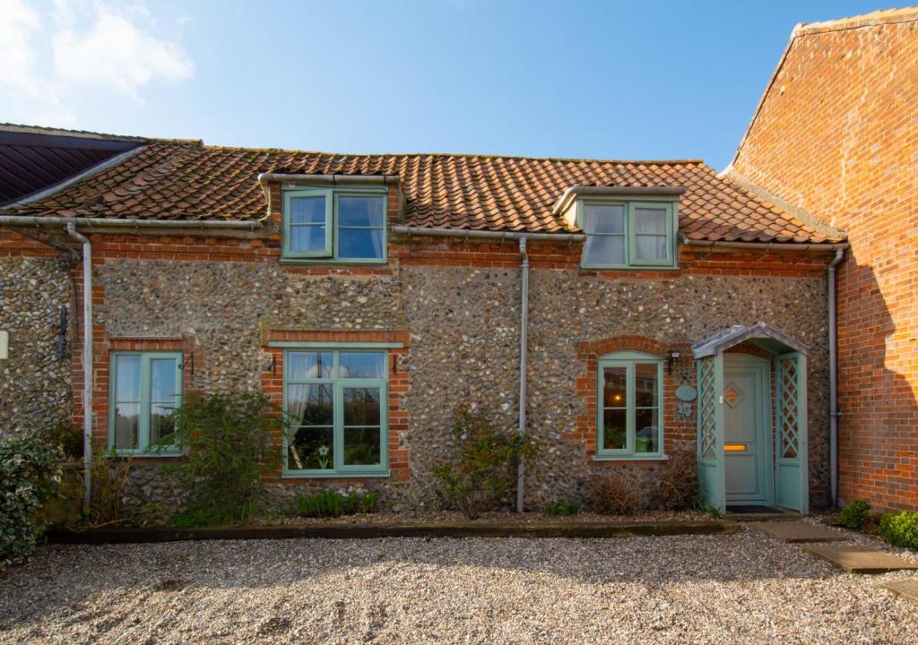 Hindringham的住宿－Shamrock Cottage，一间设有蓝色门窗的砖房