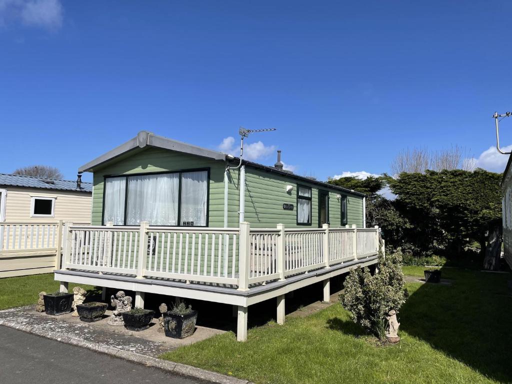 a green house with a porch and some plants at 6 berth pet friendly caravan on Sandy Glade (John Fowlers) Brean in Berrow