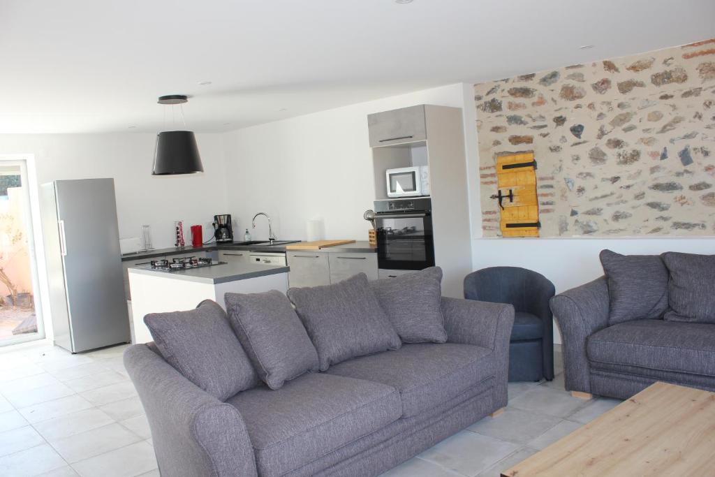 a living room with a couch and a kitchen at Gîte de charme pour 10 personnes in Camélas