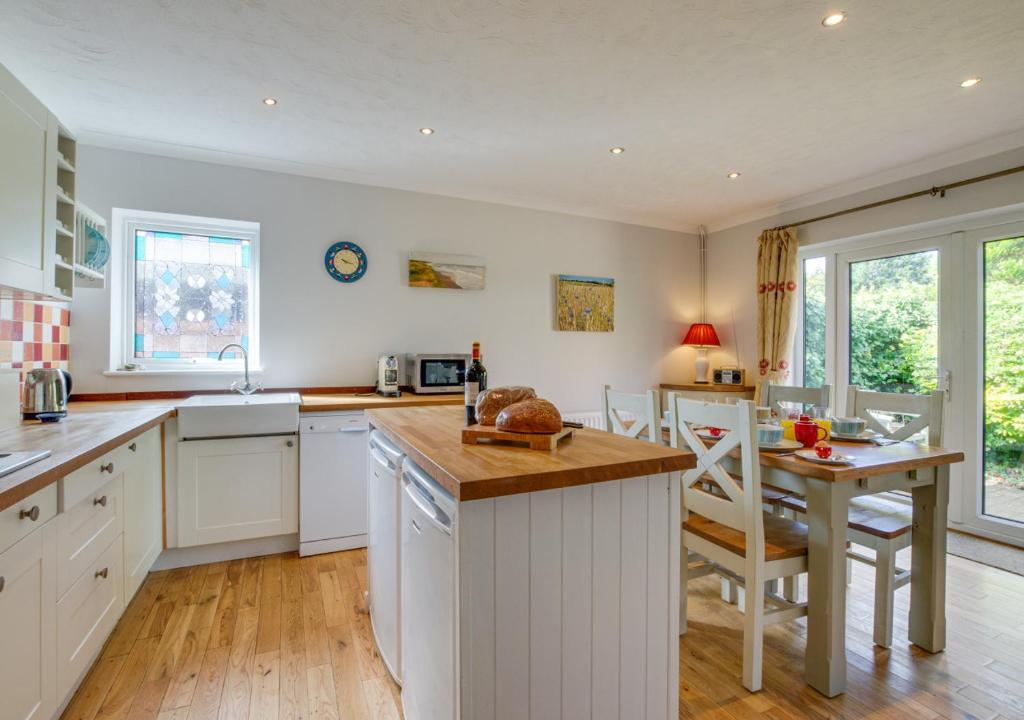 a kitchen with white cabinets and a table and a counter at Sandy Bottom in Hunstanton