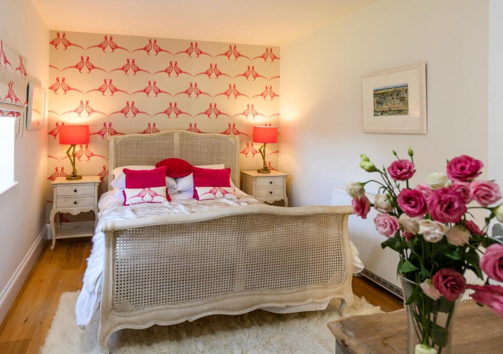 1 dormitorio con 1 cama con almohadas rojas y flores en South Lodge East, en Holkham