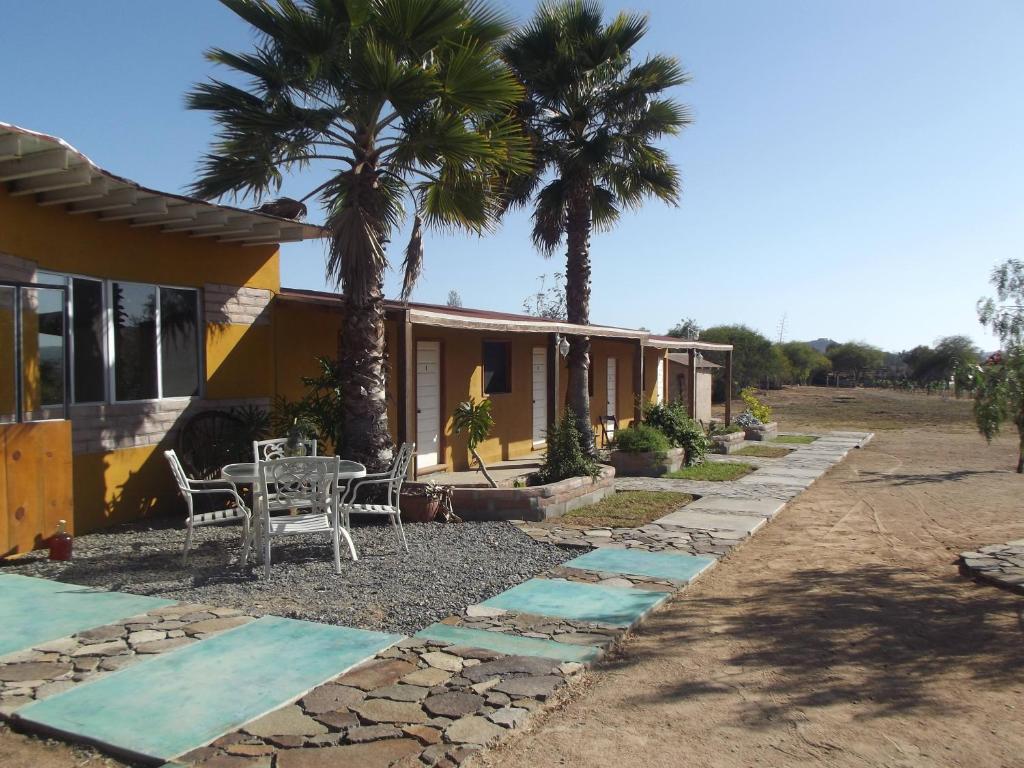 a house with a table and palm trees in front of it at Casa Campo Rancho Villarino in Ensenada