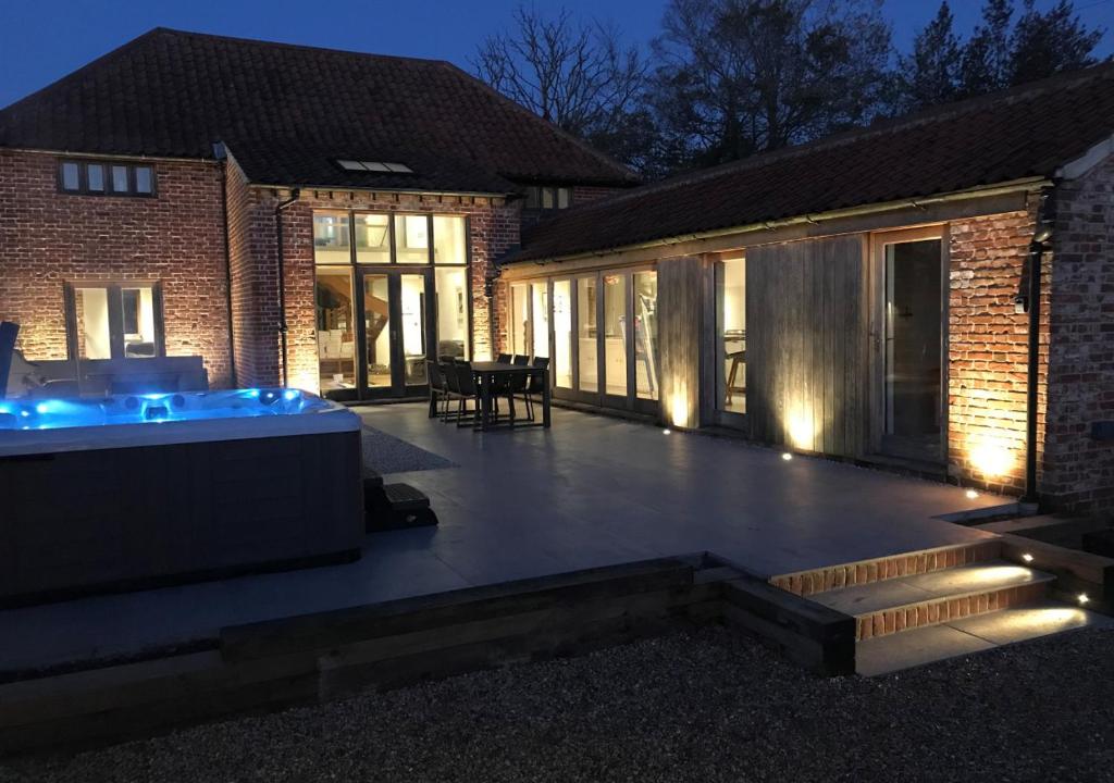 a large patio with a hot tub in front of a building at The Granary in Banningham