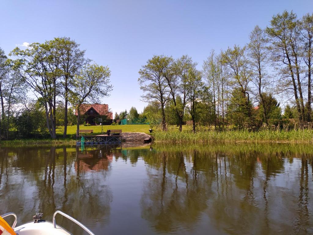 un barco en un lago con una casa en el fondo en Dom z bala z prywatnym kortem i plażą, en Krzywe