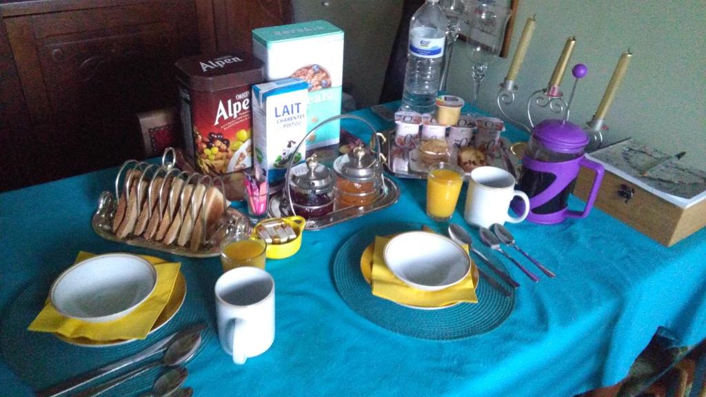 a blue table with plates and utensils on it at white house in Saint-Germier