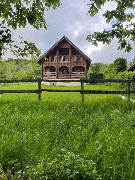 une maison en bois dans un champ avec une clôture dans l'établissement Au bord du lac III, à Montigny-en-Morvan