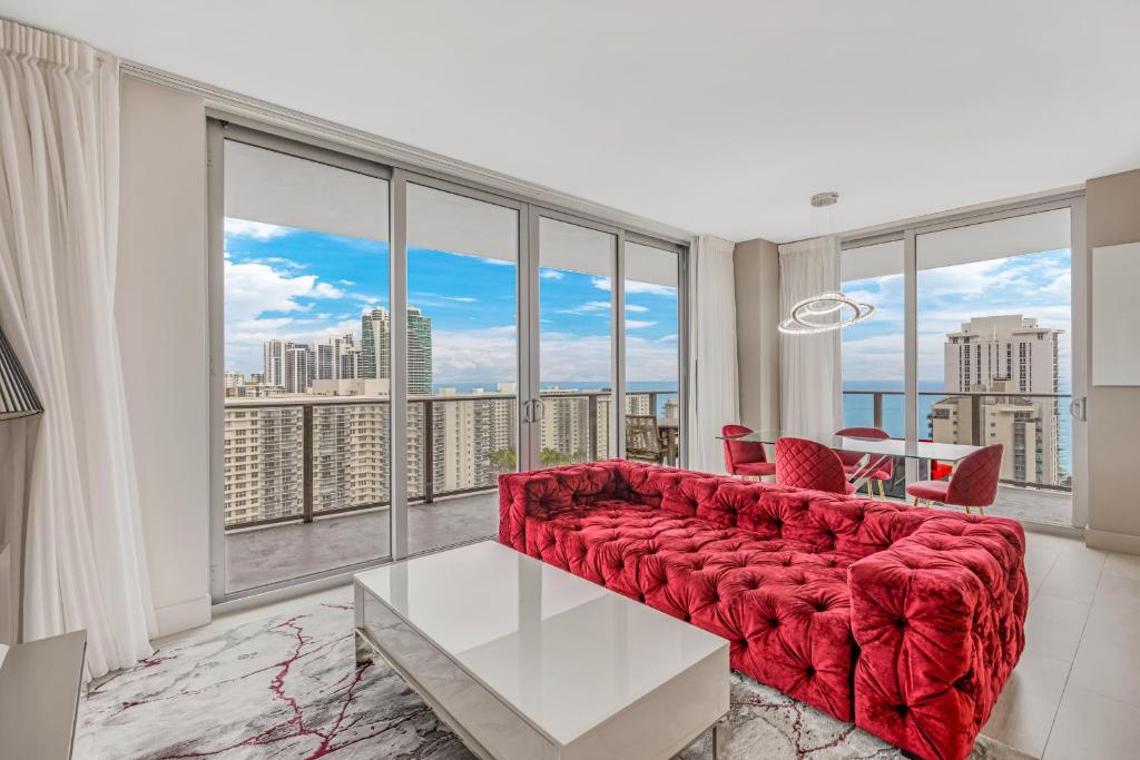 Una sala de estar con un sofá rojo y grandes ventanales. en Hyde Beach House Resort - 2BD-2BA Ocean View Luxury Resort - 5 MIN FROM BEACH - 6 GUESTS, en Hollywood