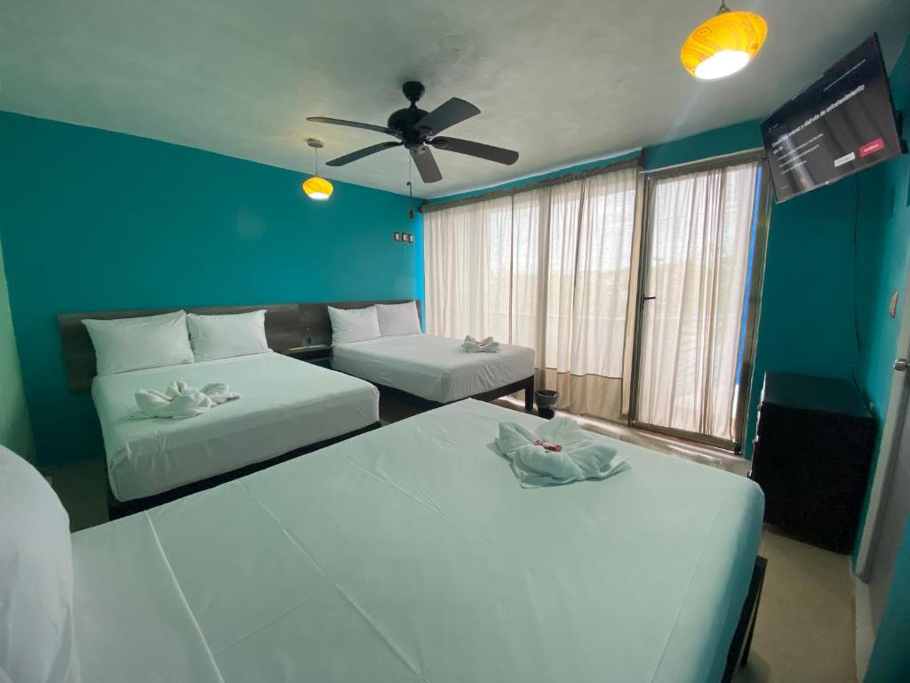 a bedroom with two beds and a ceiling fan at Hotel Murallas Capital in Campeche