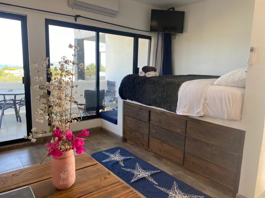 ein Schlafzimmer mit einem Bett und einer Vase mit Blumen auf dem Tisch in der Unterkunft Casa Arrecife - Cozy Suite, Fast Wifi & Balcony! Beach is steps away! in La Ventana