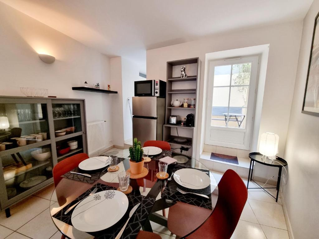 a dining room with a table and chairs and a window at Coquette maison de ville calme avec patio in Angoulême