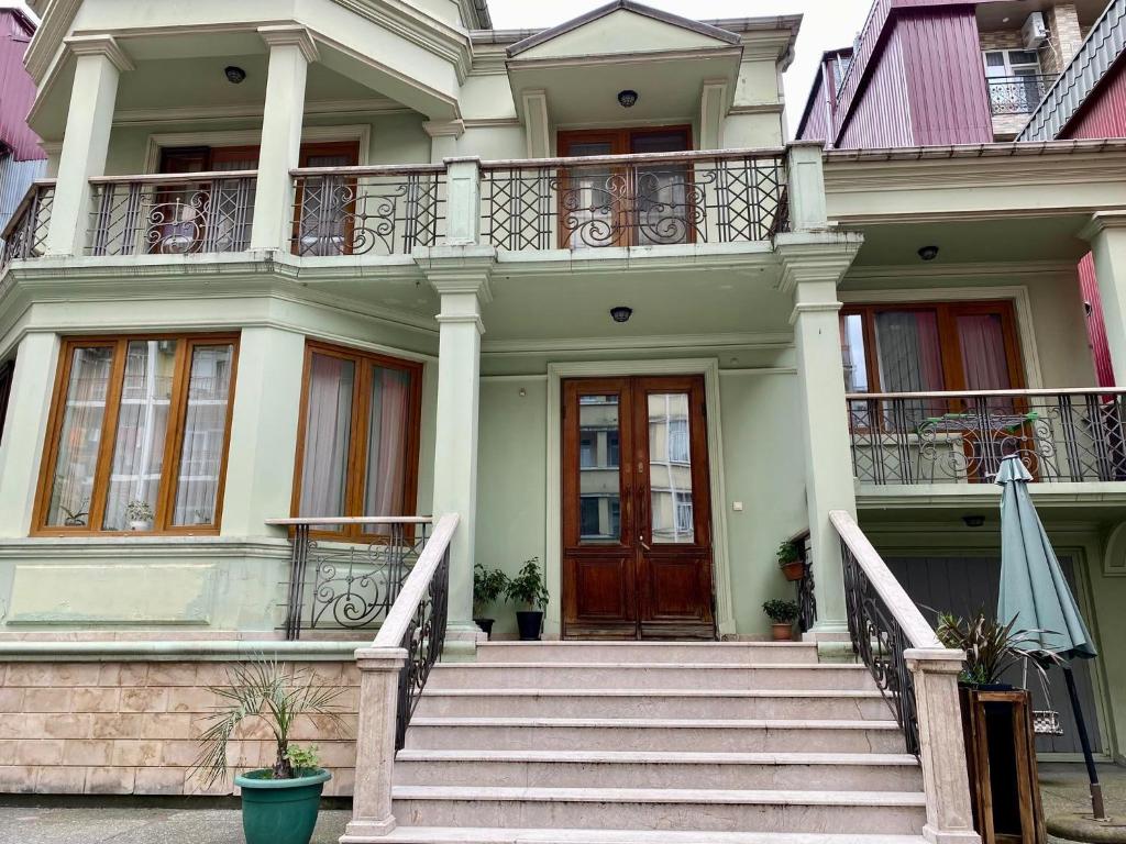a white house with stairs and a wooden door at Guesthouse Parnavaz Mepe in Batumi
