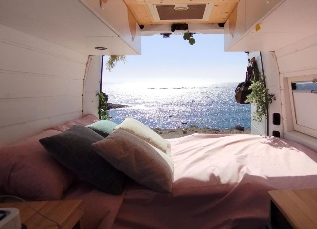 a bed in a room with a view of the ocean at Sleepfurgo in Las Palmas de Gran Canaria