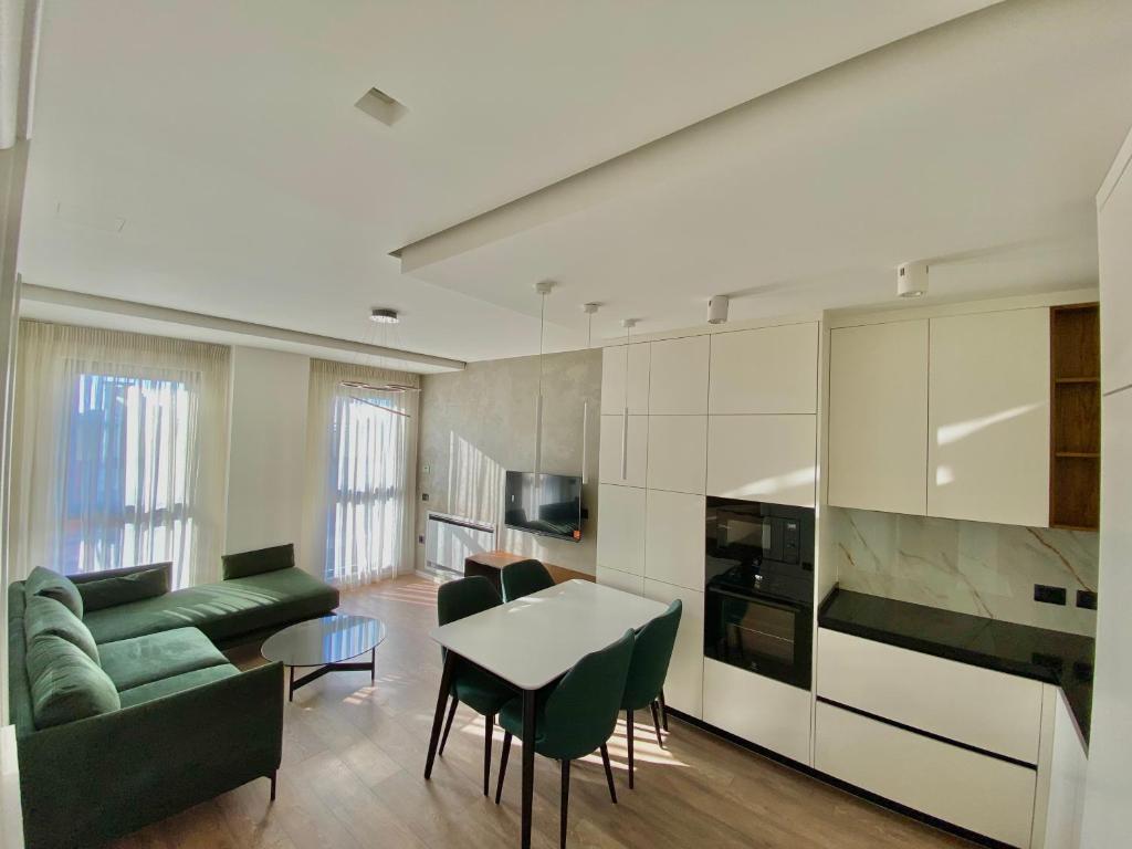 eine Küche und ein Wohnzimmer mit einem grünen Sofa und einem Tisch in der Unterkunft Lux Apartment 02 + Free Parking Post in Tirana
