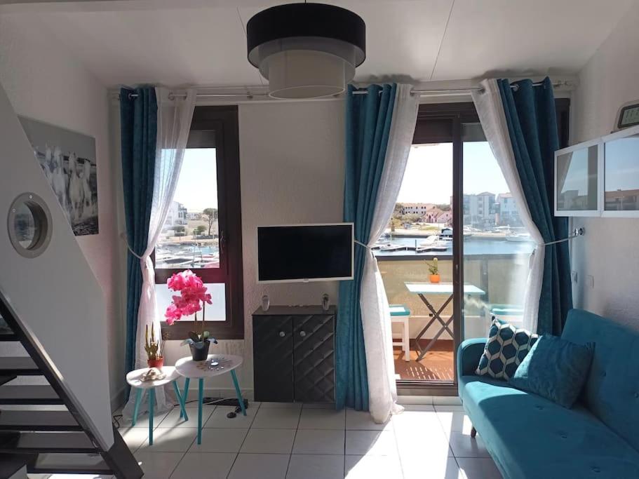 een woonkamer met een blauwe bank en een televisie bij Le bonheur entre Lac et Mer in Le Barcarès