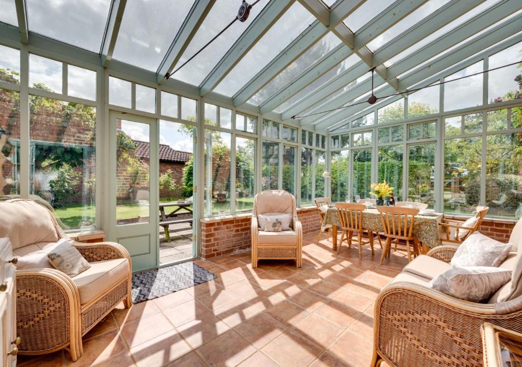 a conservatory with a glass ceiling and a table and chairs at Watts Cottage in Upton