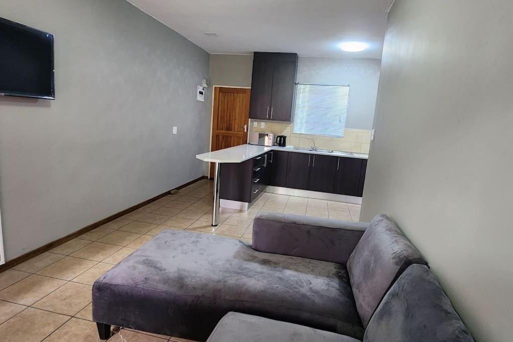 a living room with a couch and a kitchen at Apartment Near Amajuba Mall in Newcastle