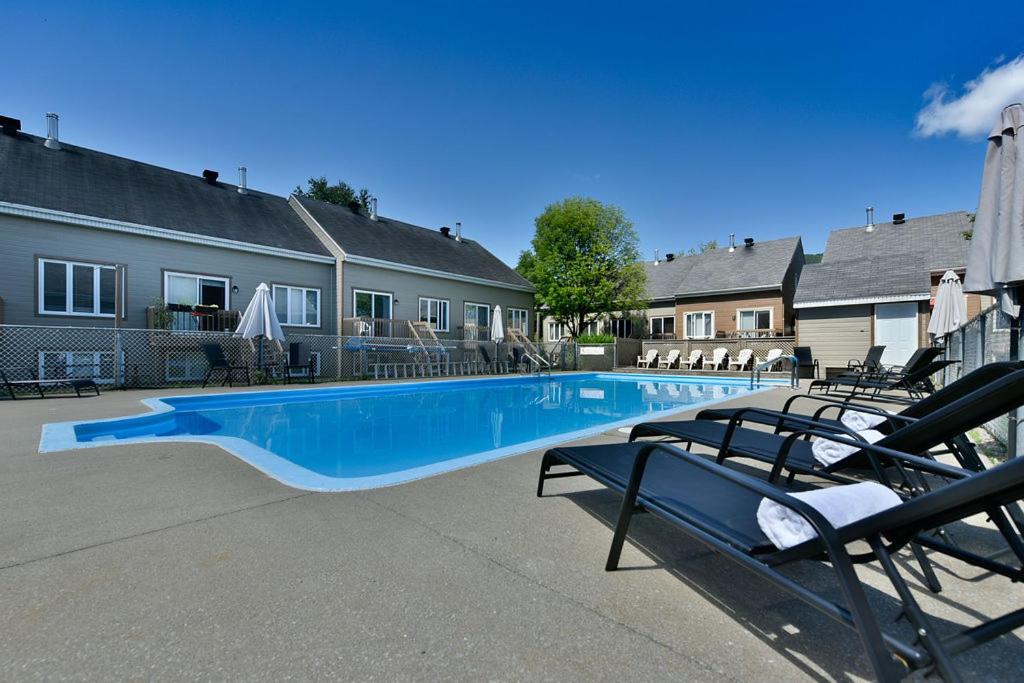 a large blue swimming pool in a yard with chairs at Hébergement Mont-Ste-Anne Condos in Beaupré