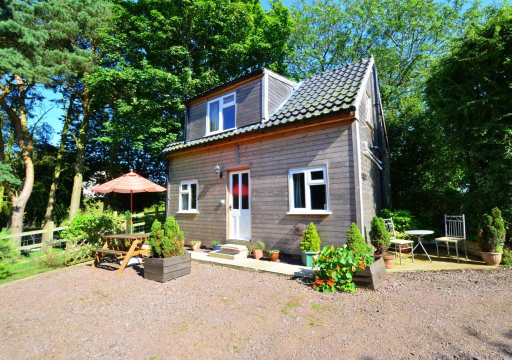 a tiny house with a table and an umbrella at The Studio in Northrepps