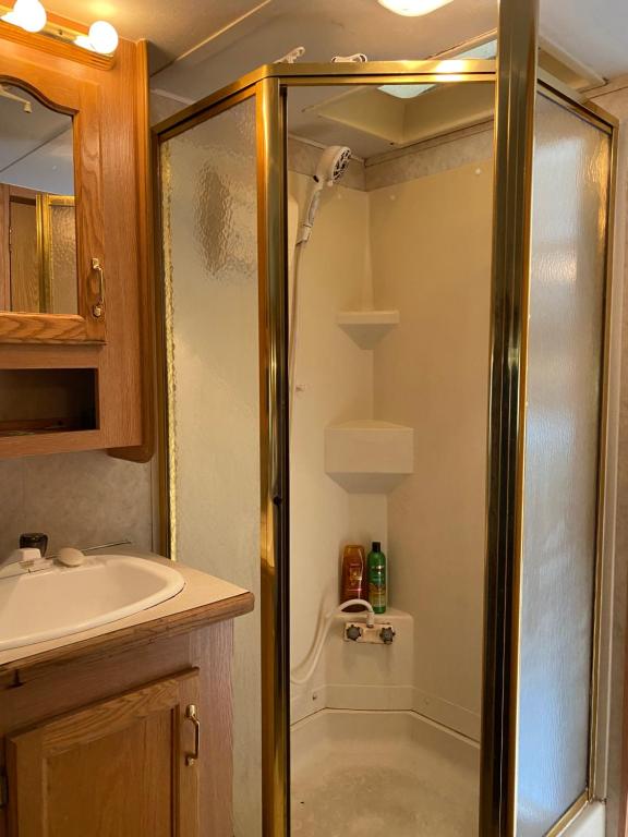 uma casa de banho com um chuveiro e um lavatório. em Comfortable RV in a farm em Nanoose Bay