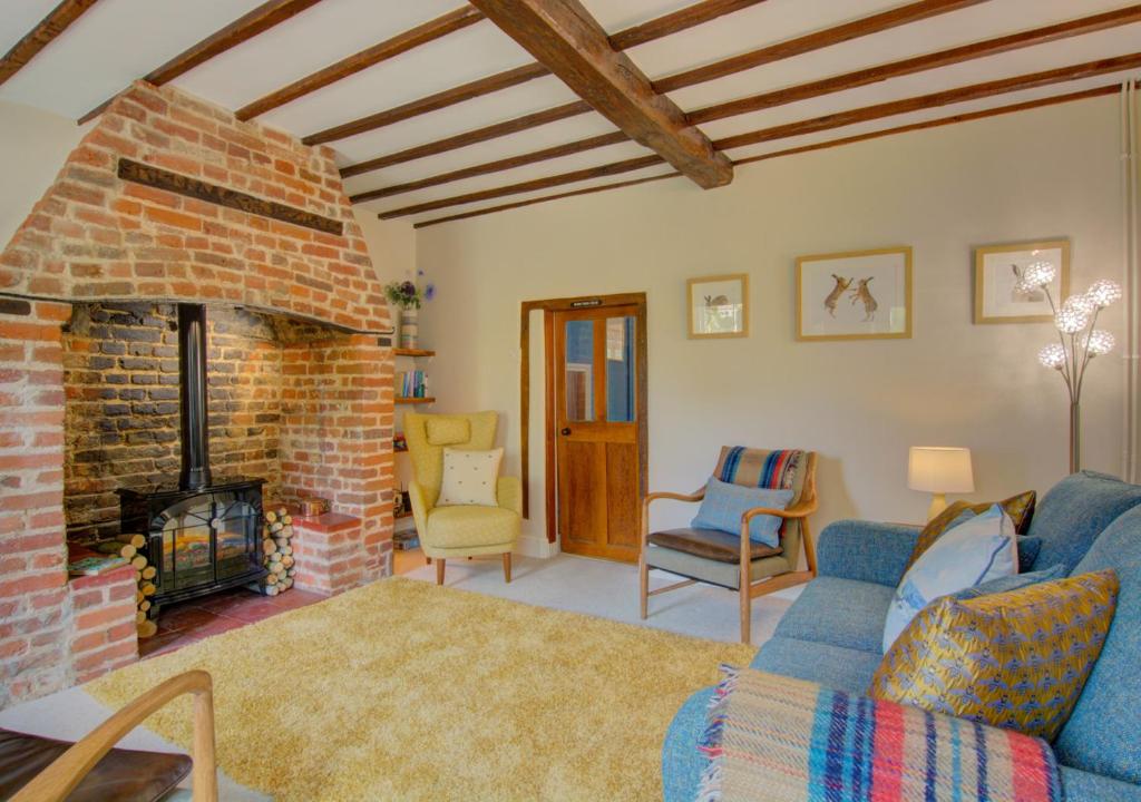 sala de estar con sofá y chimenea de ladrillo en Wren Cottage en Aylsham