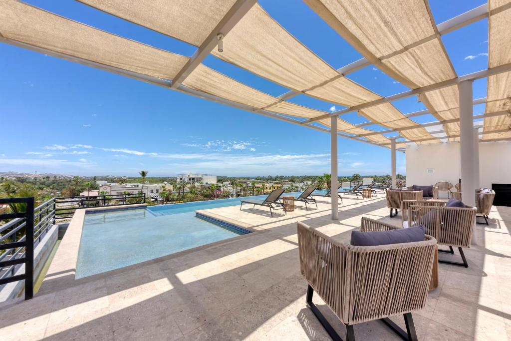 an outdoor patio with a pool and chairs and a roof at Lumina at Cardinal San José del Cabo in San José del Cabo