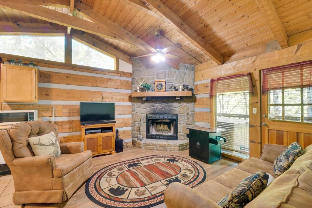 a living room with a stone fireplace in a log cabin at Gatlinburg Cabin with Hot Tub about 6 Mi to Downtown! in Gatlinburg