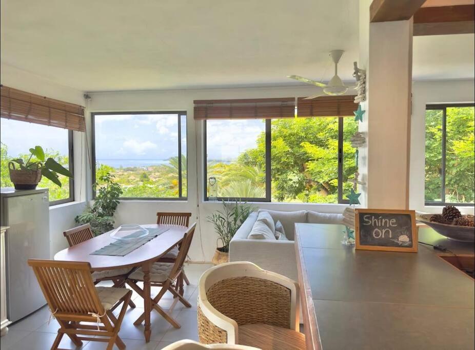 a living room with a table and chairs and windows at Seaview Sunset Apartment in Tamarin
