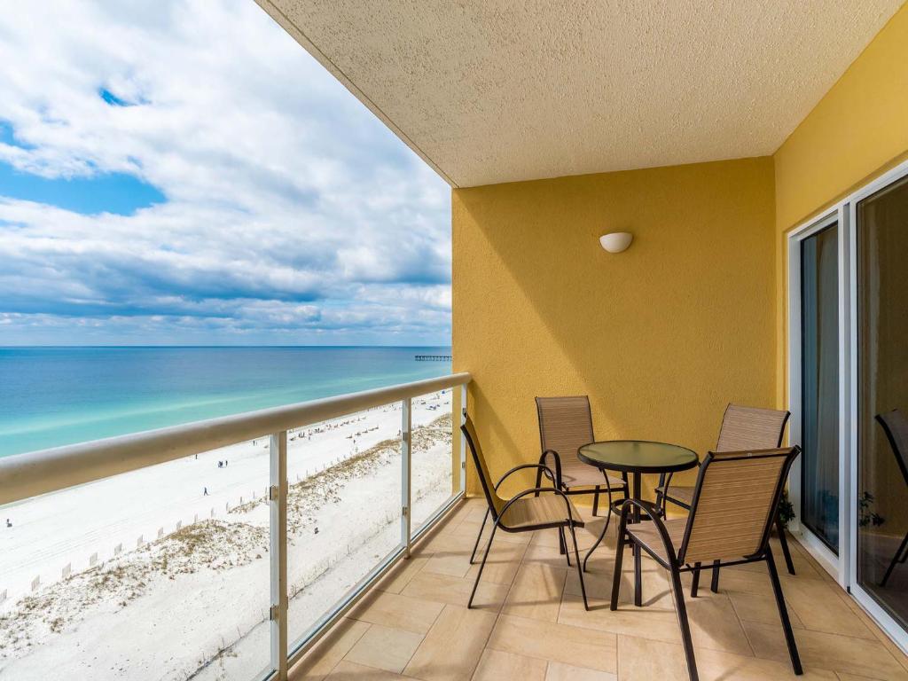 Un balcón con mesa y sillas y la playa. en Emerald Isle #1007, en Pensacola Beach