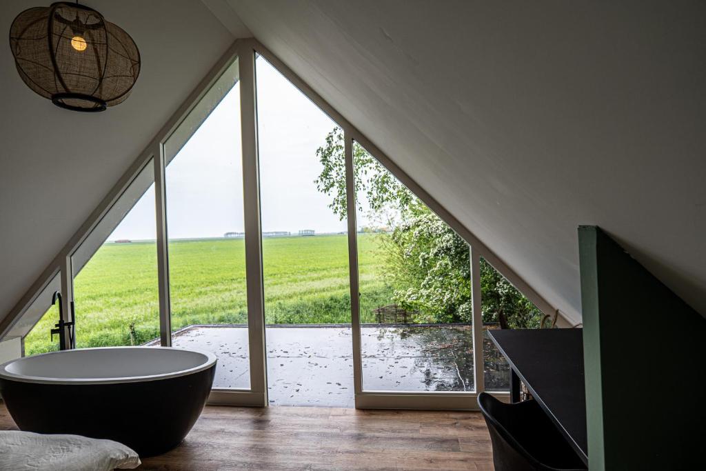 a bathroom with a large tub in front of a window at Luxe Vakantiehuis Zeeland in Wilhelminadorp