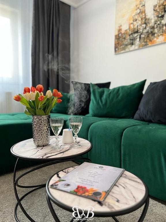 a living room with two tables and a green couch at B&B Apartment in Oţelu Roşu