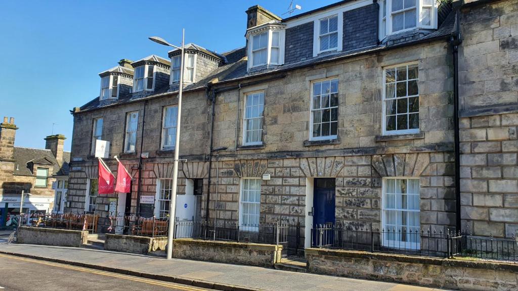 a stone building with two flags on a street at Dunperrogh in St. Andrews