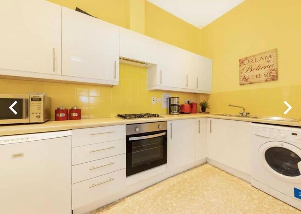 a kitchen with white cabinets and a washer and dryer at Keysan House in London