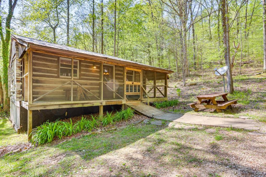 a wooden cabin in the woods with a picnic table at Historic Log Cabin with Porch Near Patoka Lake! in Taswell