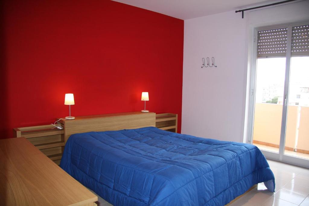 トラーパニにあるAppartamento Giglioのベッドルーム1室(青いベッド1台、赤い壁付)