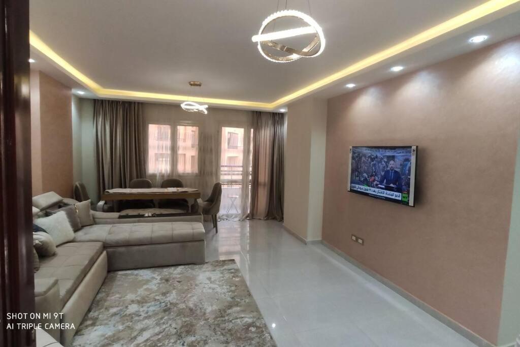 a living room with a couch and a tv on a wall at شقة للإيجار المفروش المدد القصير بكمبوند سما القاهرة. in Cairo