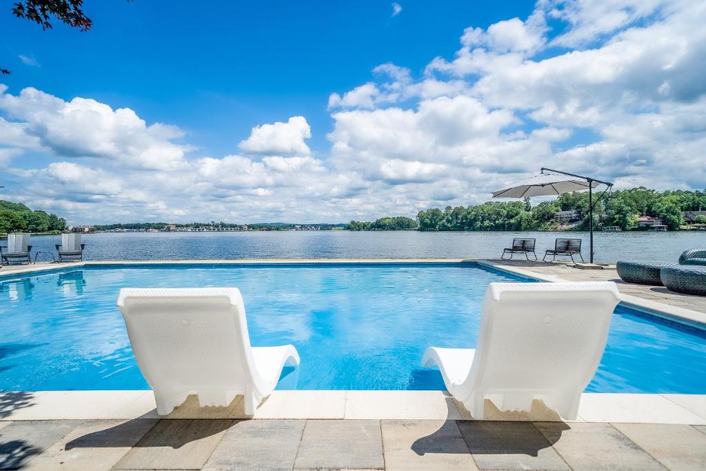 a swimming pool with two white chairs and a body of water at Ledgerwood Point in Hot Springs