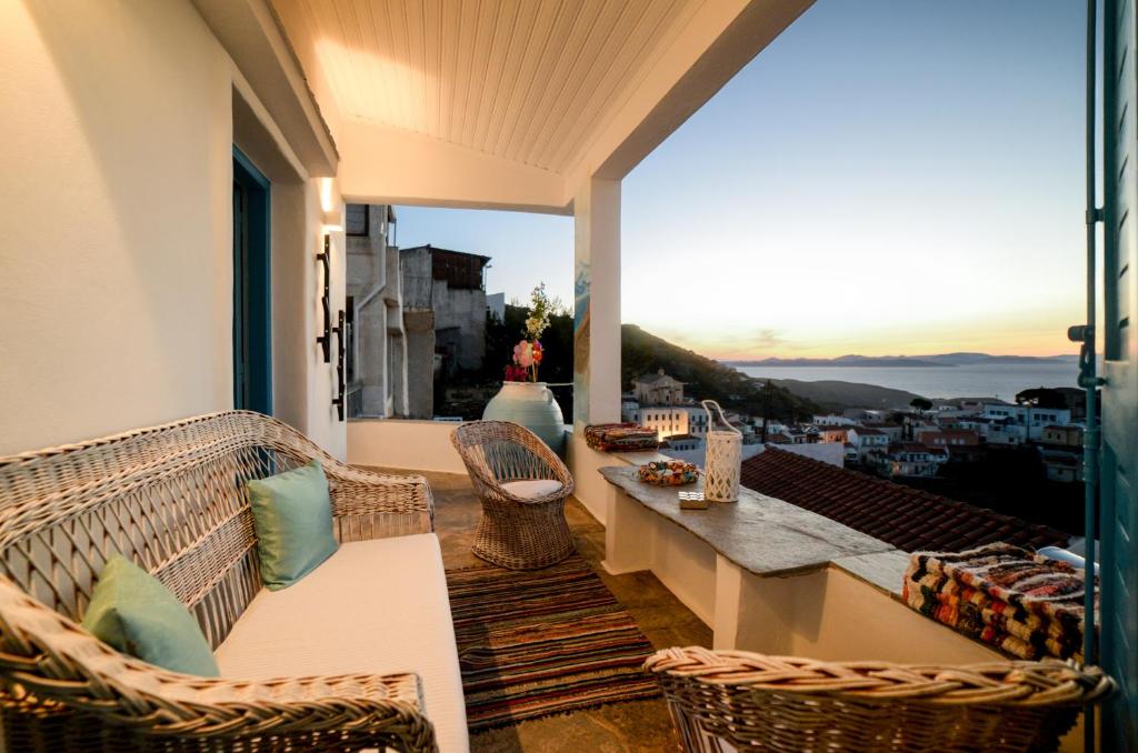 balcón con sillas de mimbre y mesa con vistas en Sunset Suite Elena en Ioulida