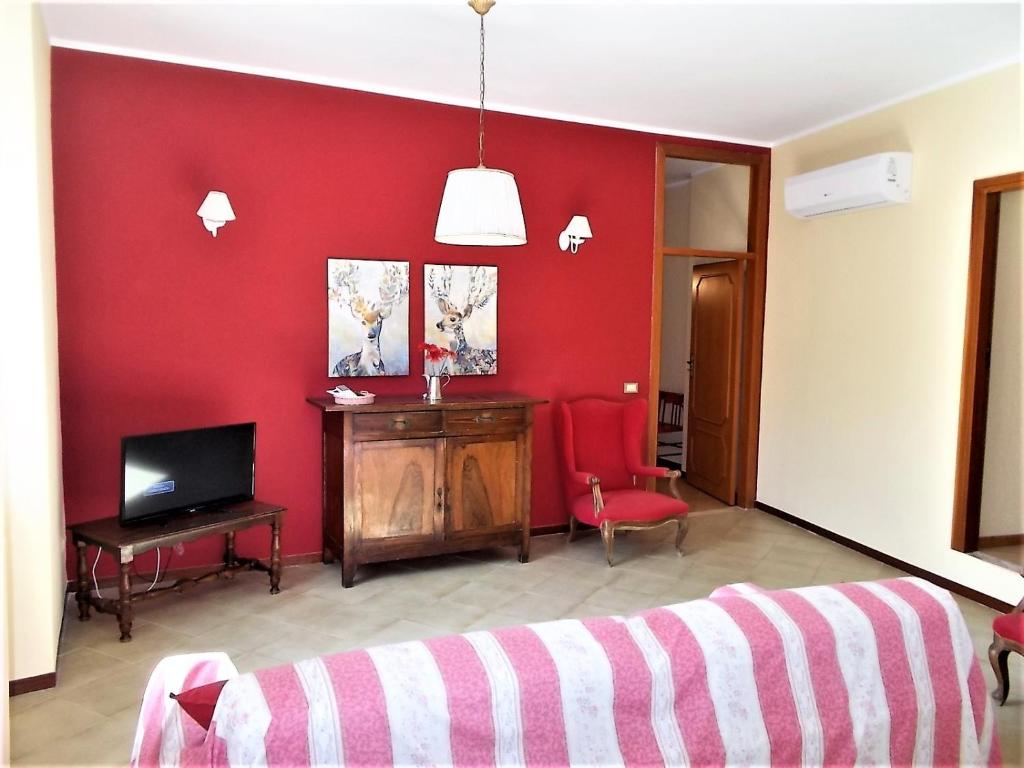 uma sala de estar com uma parede vermelha e uma televisão em Angelica em Pisciotta