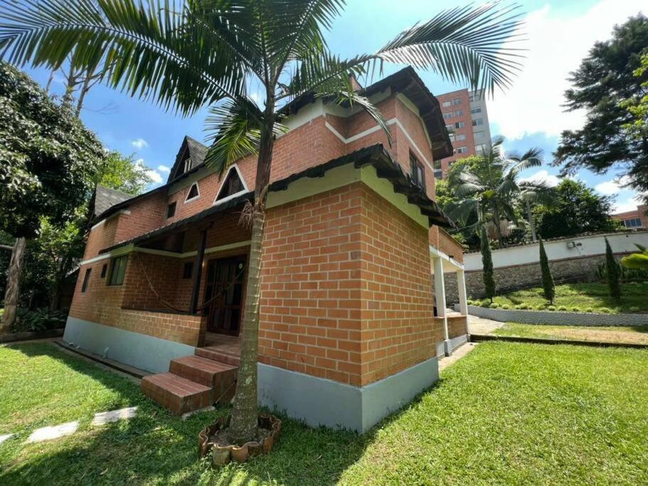 een klein bakstenen gebouw met een palmboom in de tuin bij Casa en envigado ubicación perfecta para disfrutar de la naturaleza y la ciudad in Envigado